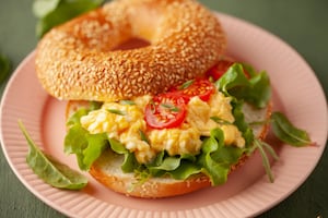 Bagel con huevo revuelto, rúcula y tomate