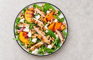 Ensalada de duraznos grillados, hojas verdes, queso y frutos secos
